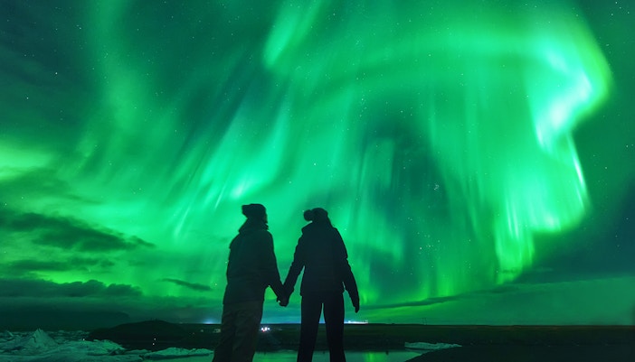 Tourists viewing Northern Lights in Iceland's night sky.