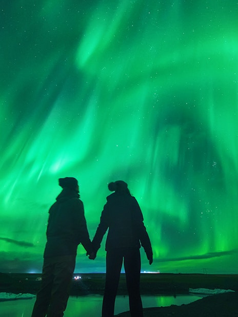 Tourists viewing Northern Lights in Iceland's night sky.