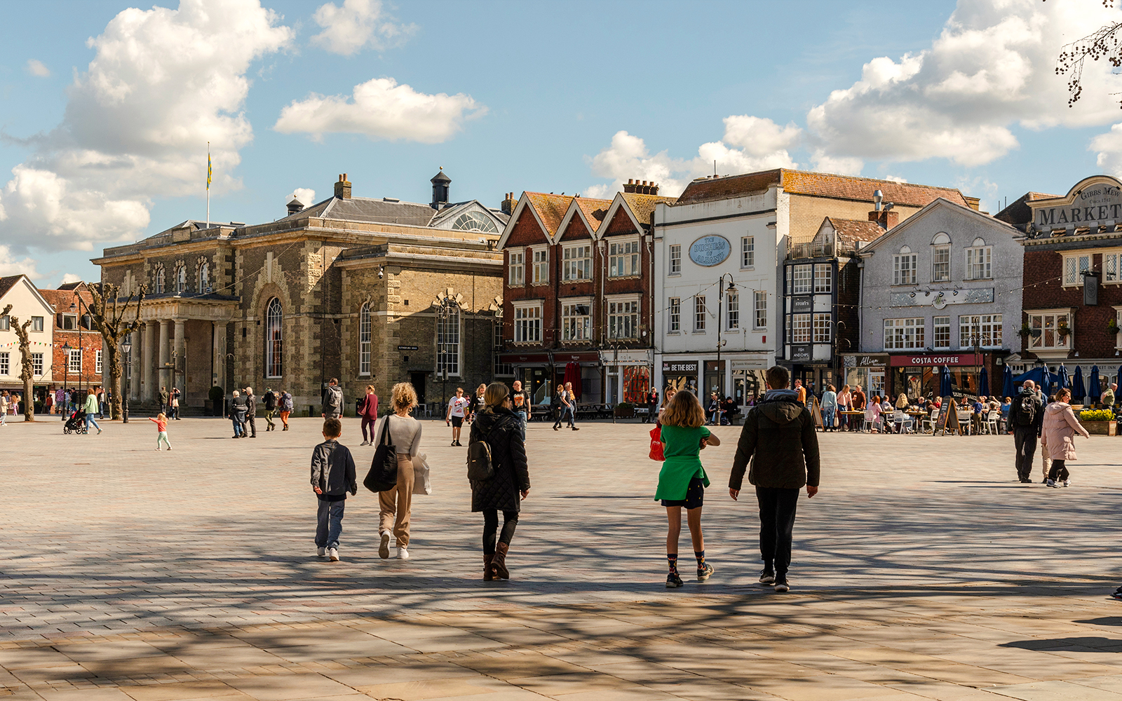 People walking in Salisbury Market Square, surrounded by historic buildings.