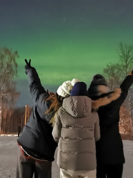 Friends watching northern lights in Lapland.