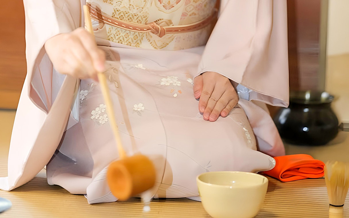 Tea ceremony participant in kimono preparing tea in Kyoto.