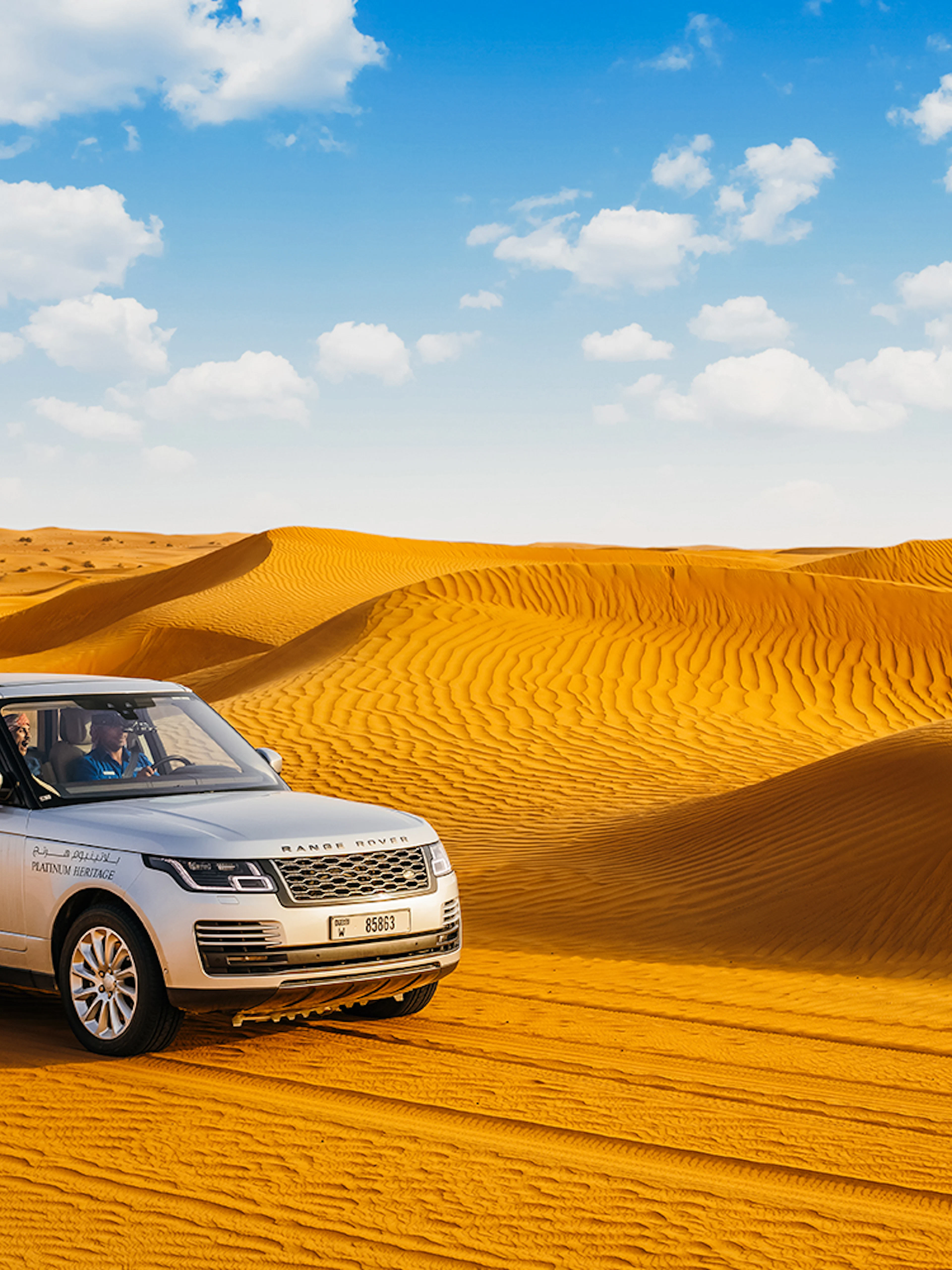 Range Rover driving through desert dunes on a safari tour.