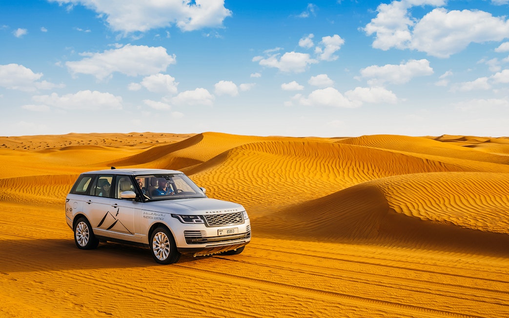 Range Rover driving through desert dunes on a safari tour.