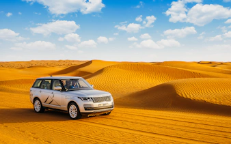 Range Rover driving through desert dunes on a safari tour.
