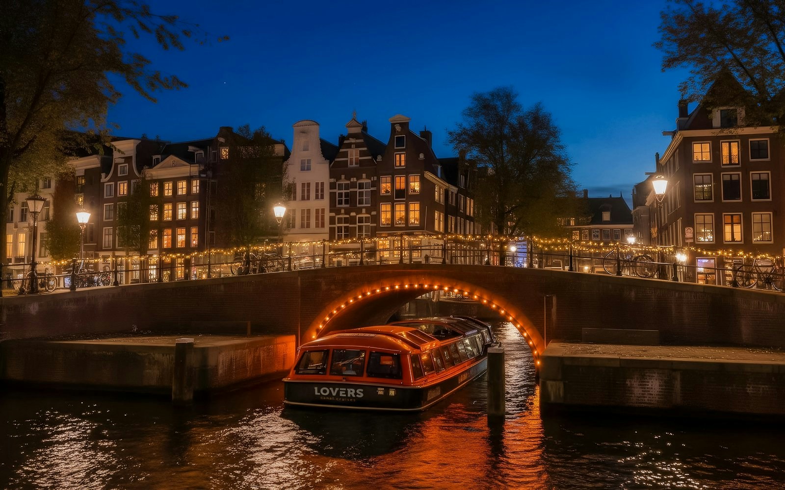 Canal boat under illuminated bridge during Amsterdam Light Festival.