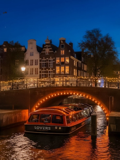 Canal boat under illuminated bridge during Amsterdam Light Festival.