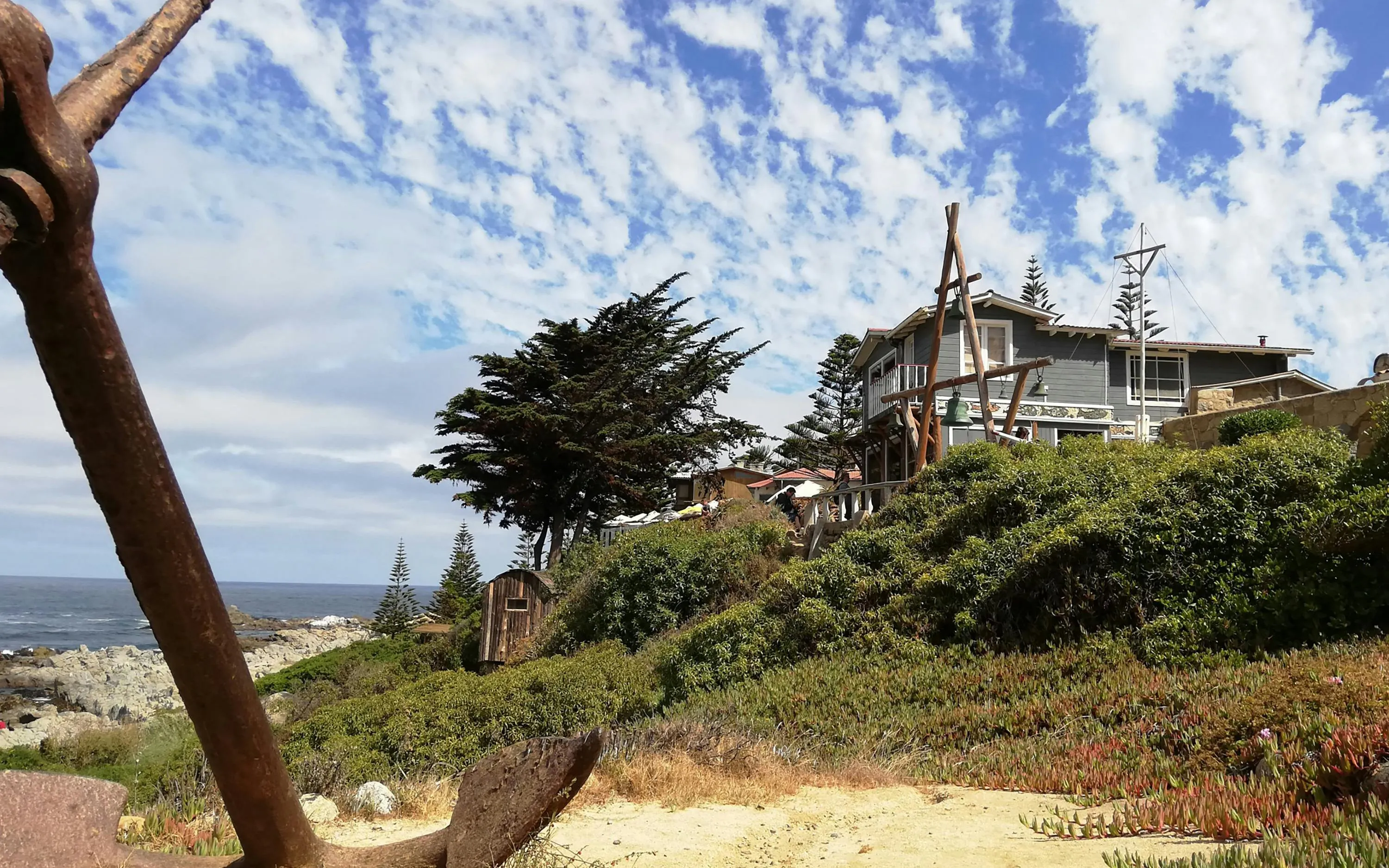 Casa de Isla Negra overlooking the Pacific Ocean, surrounded by lush greenery and coastal scenery.