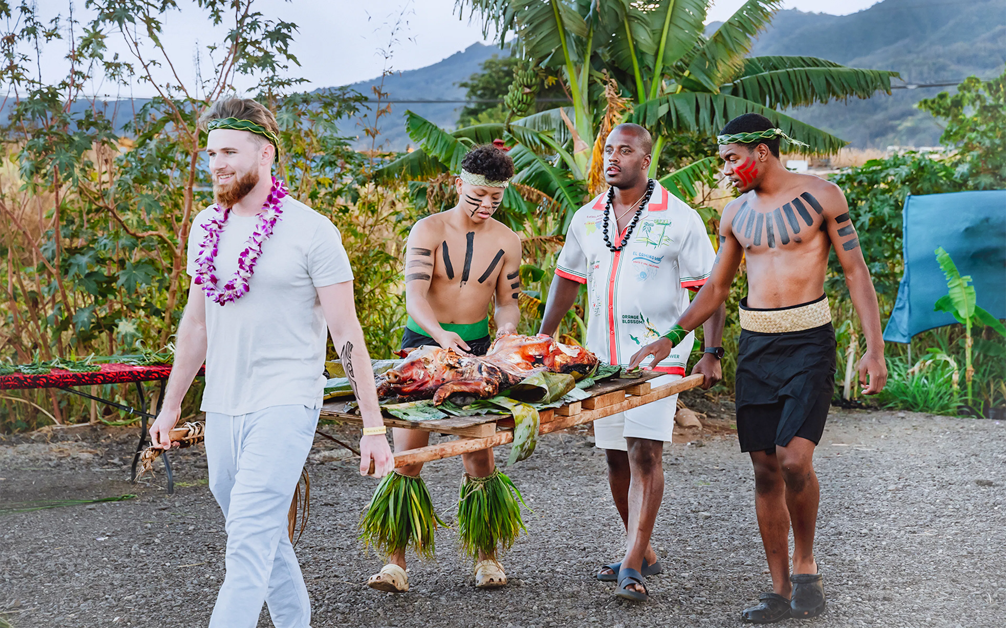 Guests carrying traditional Hawaiian roasted pig at Mauka Warriors Luau, Hawaii.