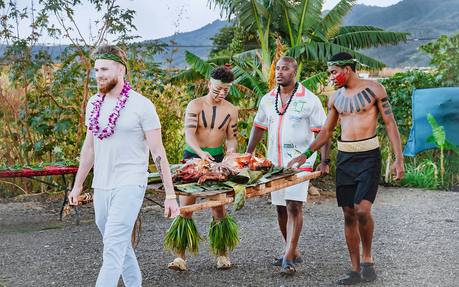 Guests carrying traditional Hawaiian roasted pig at Mauka Warriors Luau, Hawaii.