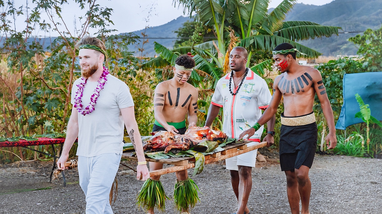 Guests carrying a traditional Hawaiian roasted pig at Mauka Warriors Luau.