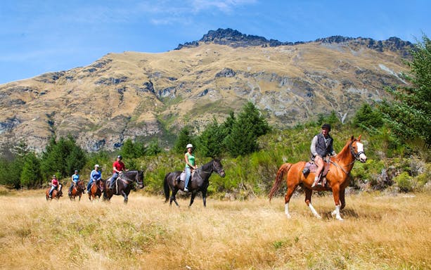 Horse trekking group at Walter Peak with mountain backdrop, Queenstown.