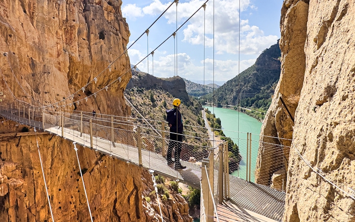 Caminito del Rey walkway with hiker overlooking river gorge in Spain.