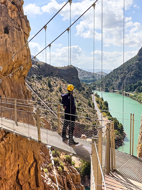 Caminito del Rey walkway with hiker overlooking river gorge in Spain.