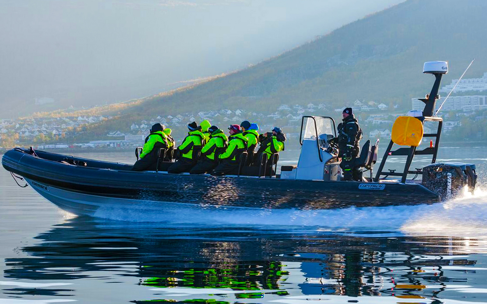 Tourists on RIB boat whale watching in icy Tromso waters, guided by expert.