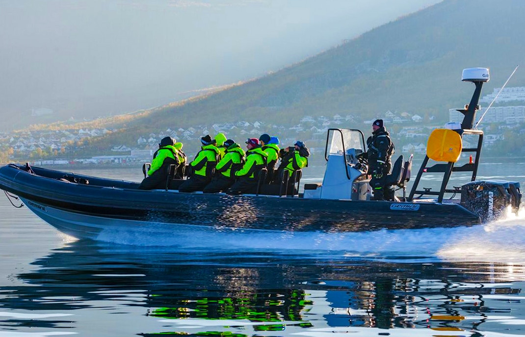 Tourists on RIB boat whale watching in icy Tromso waters, guided by expert.