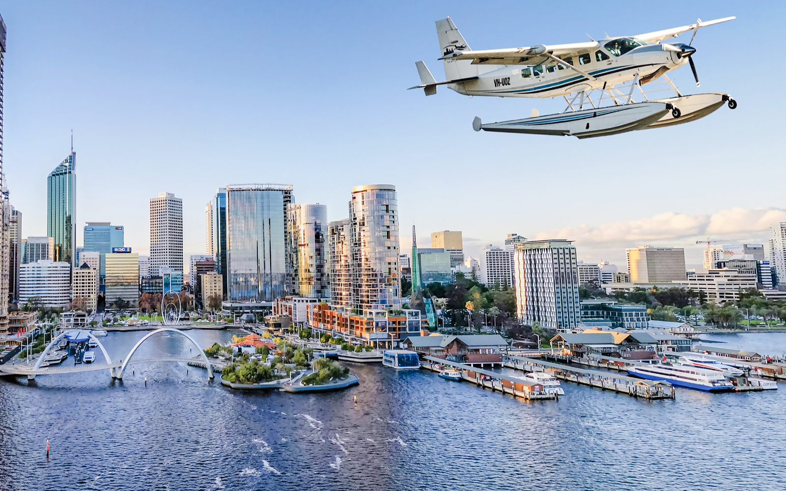 Seaplane flying over water with Perth cityscape in the background.
