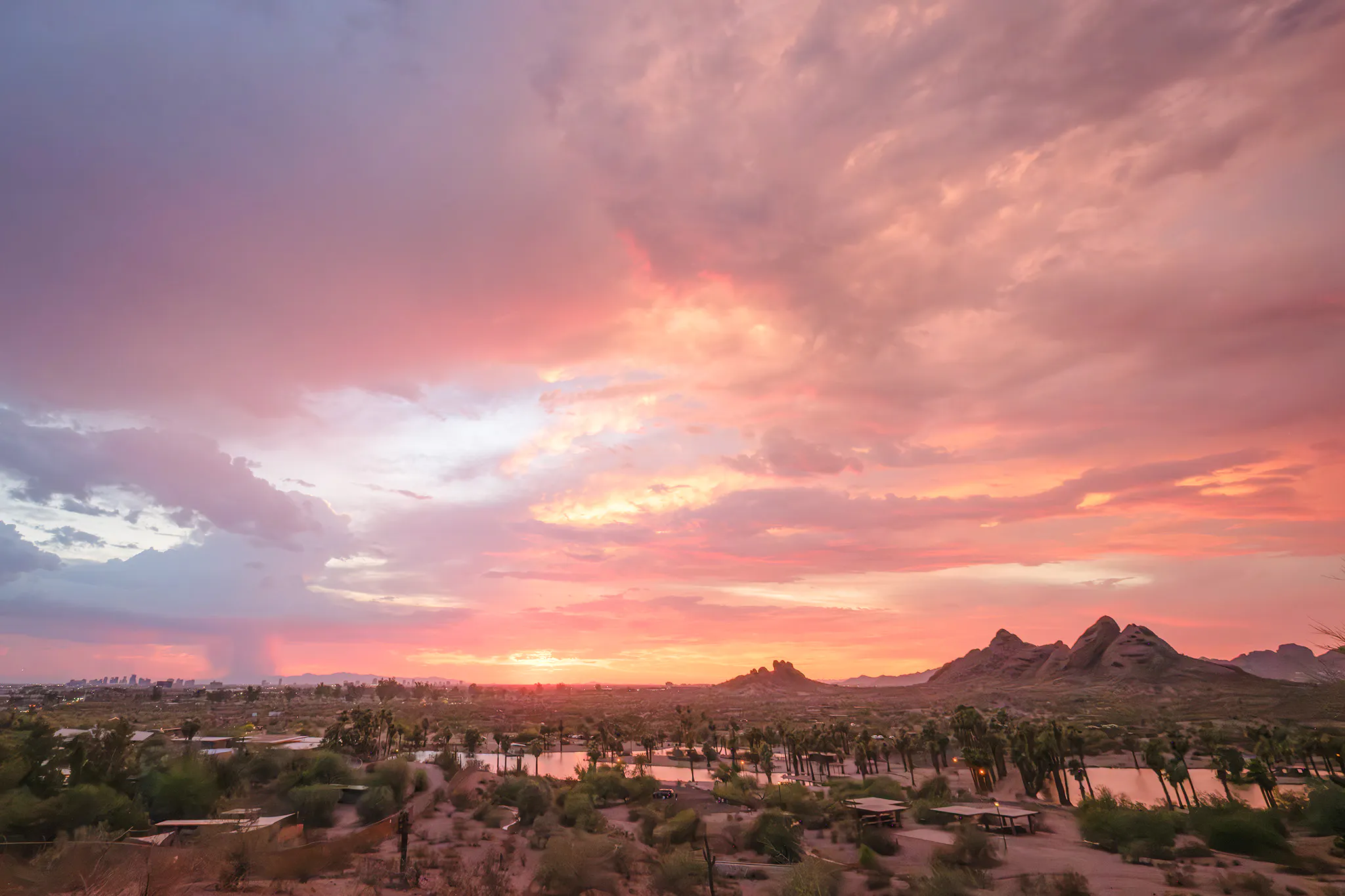 Sunset view of Papago Park with desert landscape and distant Phoenix skyline.