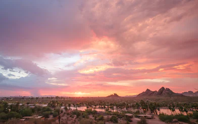 Sunset view of Papago Park with desert landscape and distant Phoenix skyline.