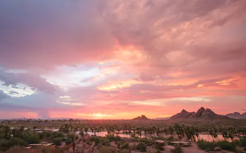 Sunset view of Papago Park with desert landscape and distant Phoenix skyline.