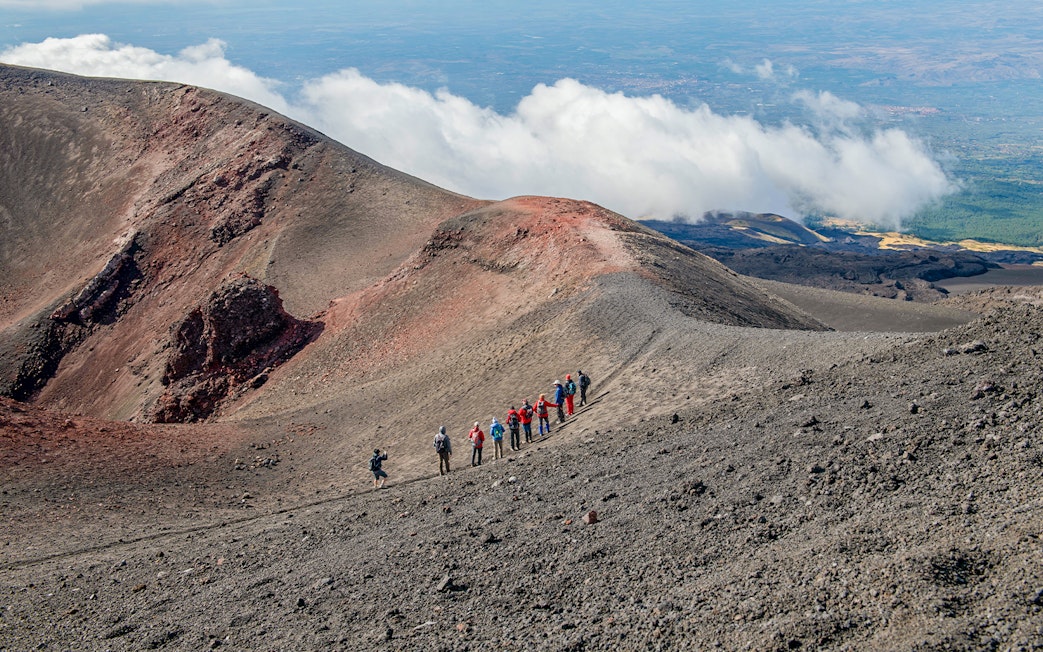 Group hiking along Mount Etna's volcanic ridge during a guided trek.
