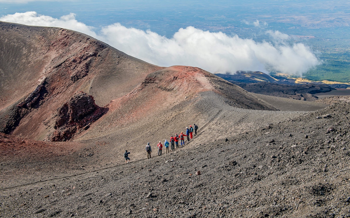 Group hiking along Mount Etna's volcanic ridge during a guided trek.