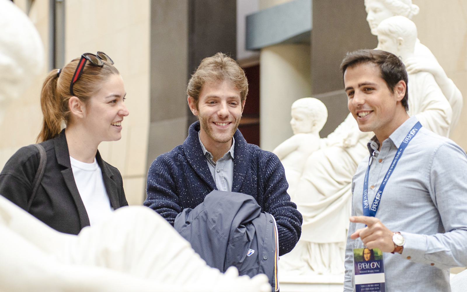 Guide with tourists inside Orsay Museum, France, discussing sculptures.