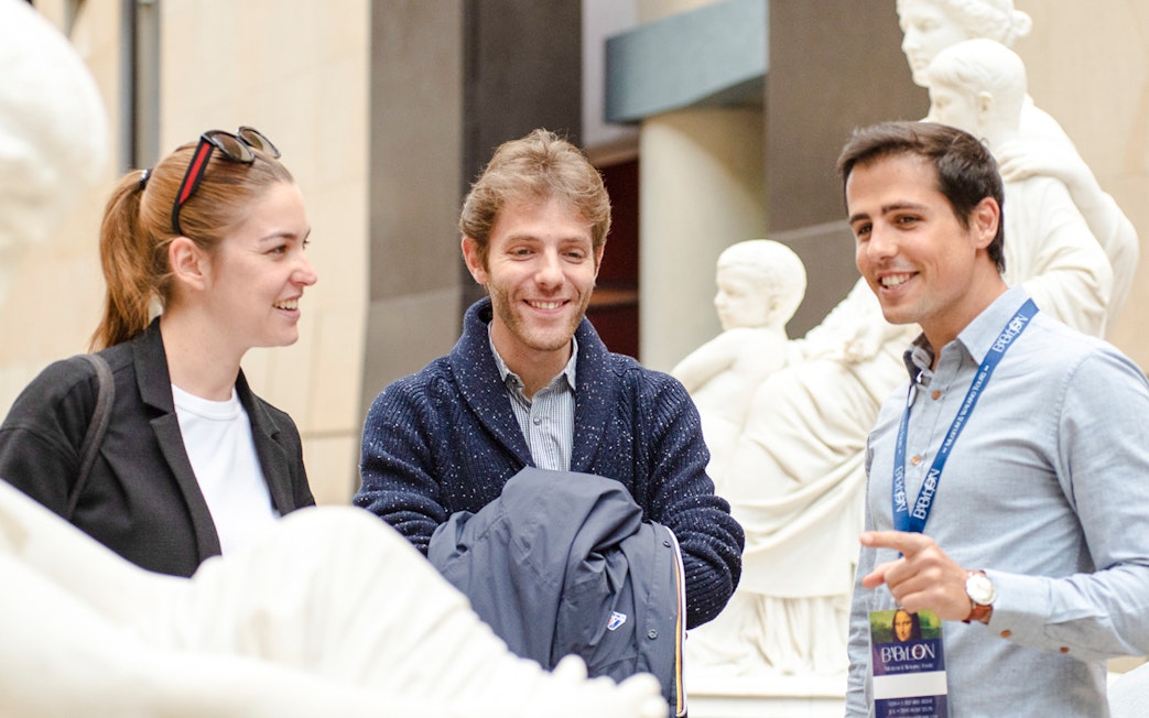 Guide with tourists inside Orsay Museum, France, discussing sculptures.