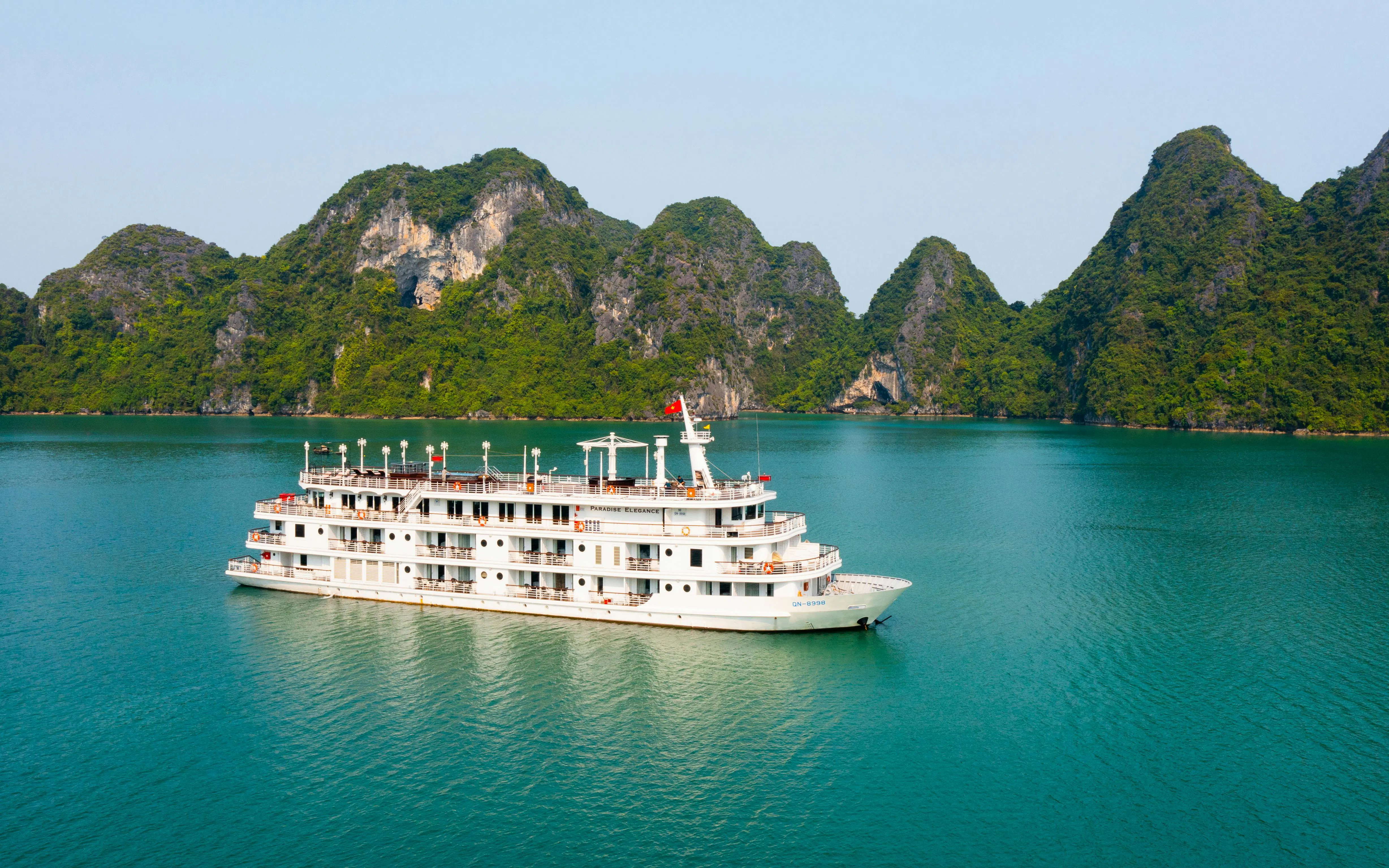 5-star cruise ship sailing in Ha Long Bay with limestone karsts in the background.