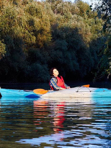 Kayaker relaxing on calm waters surrounded by lush greenery in Blue Eye, Albania.