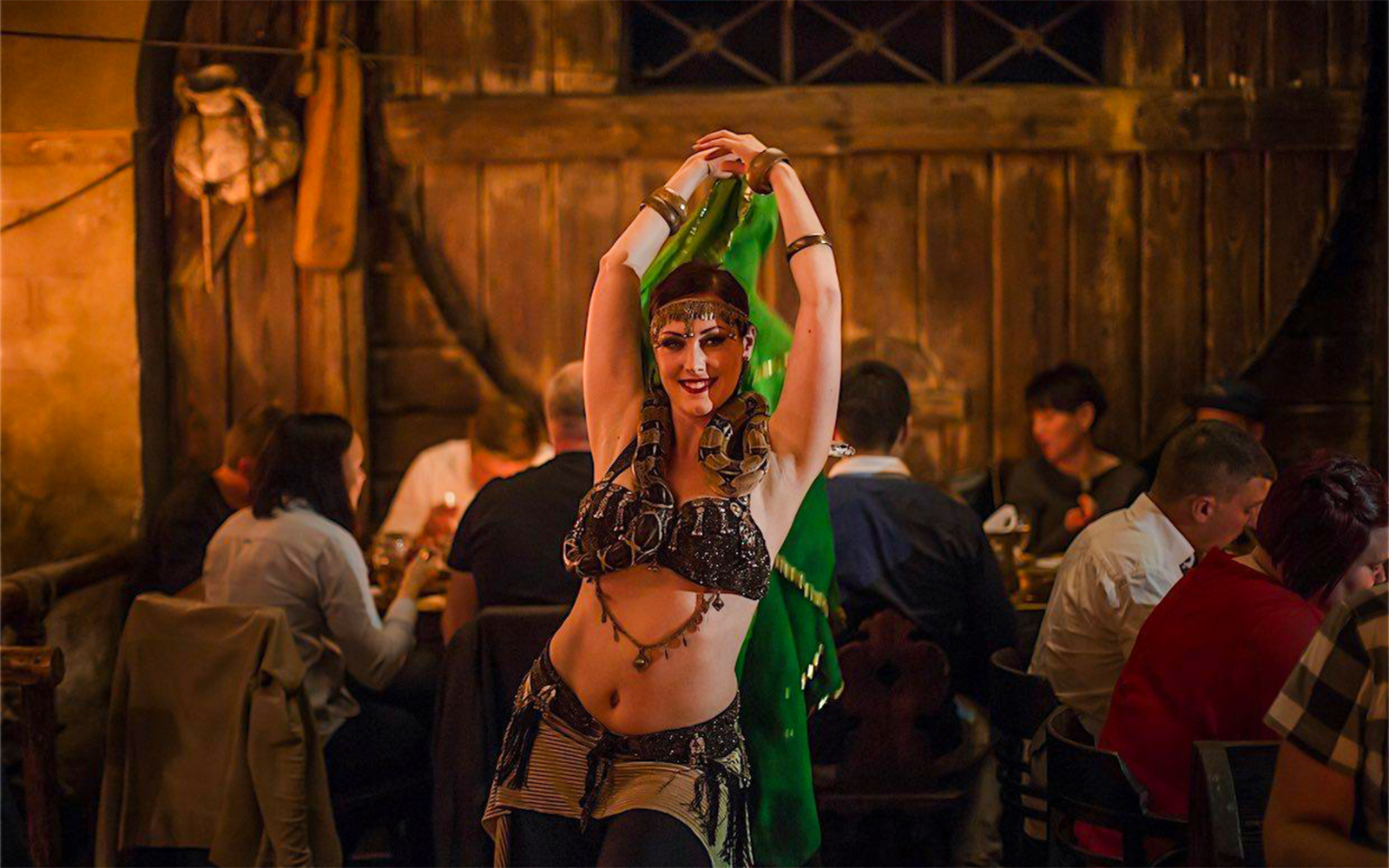 Bellydancer performing at a medieval dinner show with guests dining in the background.