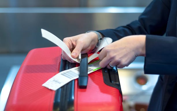 Attaching luggage tag to red suitcase at Incheon Airport.