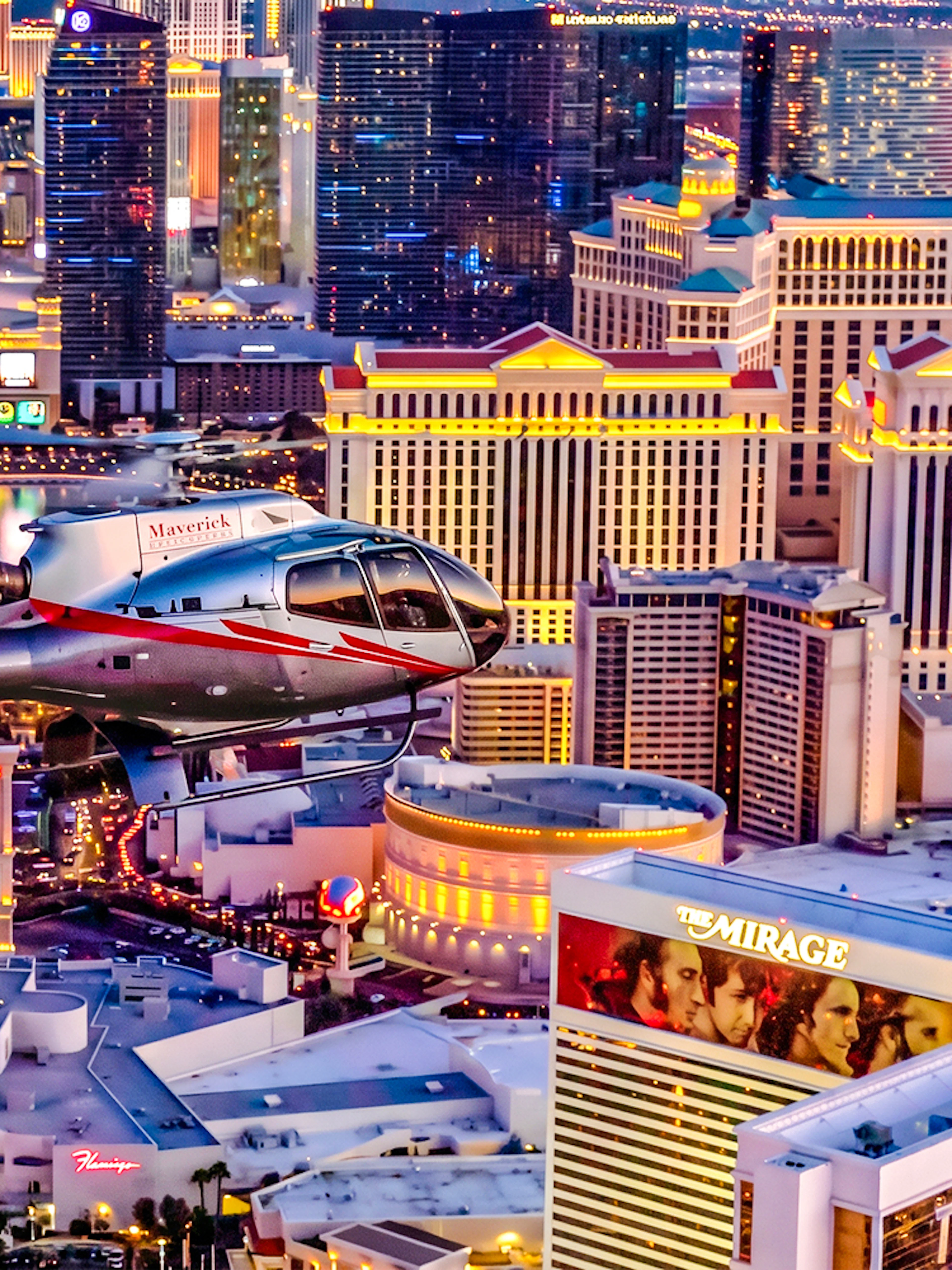 Helicopter flying over the illuminated Las Vegas Strip at night.