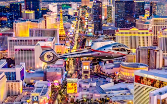 Helicopter flying over the illuminated Las Vegas Strip at night.