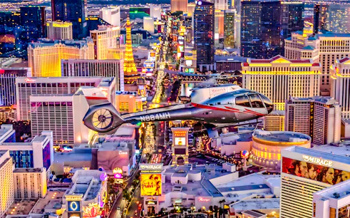 Helicopter flying over the illuminated Las Vegas Strip at night.