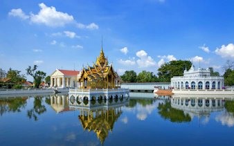 Bang Pa-In Royal Palace pavilion and surrounding buildings reflected in a serene lake.