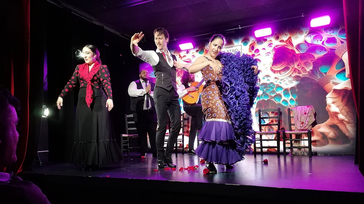 Flamenco dancers performing on stage at Teatro Flamenco with a guitarist in the background.