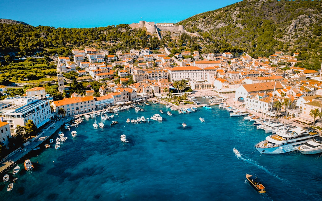 Aerial view of Komiža Island harbor with boats and historic buildings.