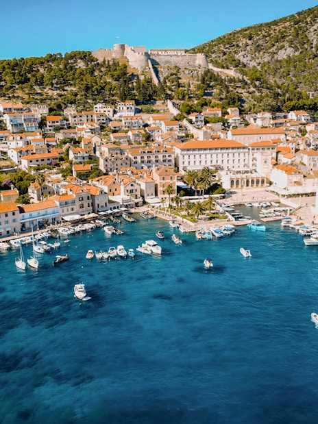 Aerial view of Komiža Island harbor with boats and historic buildings.