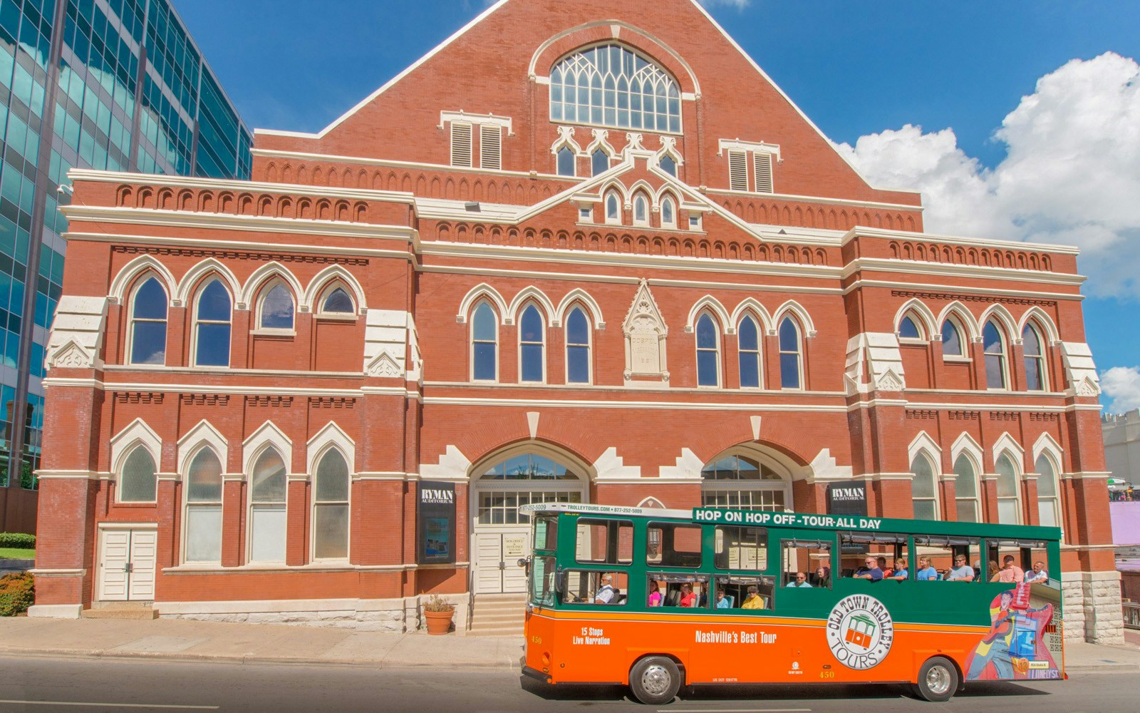 HOHO Bus passing through red-bricked Ryman Auditorium on a slanting road.