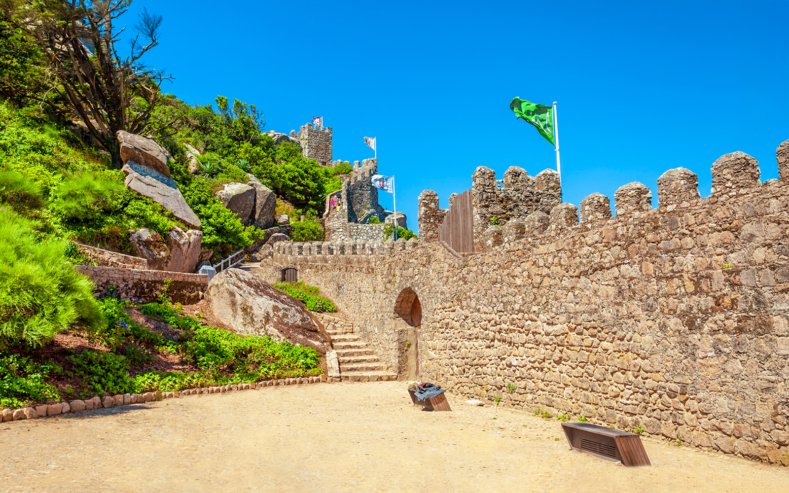 Moorish Castle gates with stone paths and flags in Sintra, Portugal.