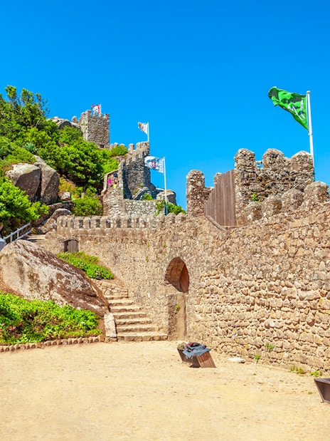 Moorish Castle gates with stone paths and flags in Sintra, Portugal.