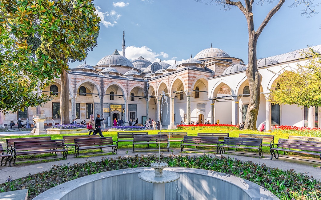 Topkapi Palace Courtyard with benches, fountain, and arched colonnade in Istanbul.