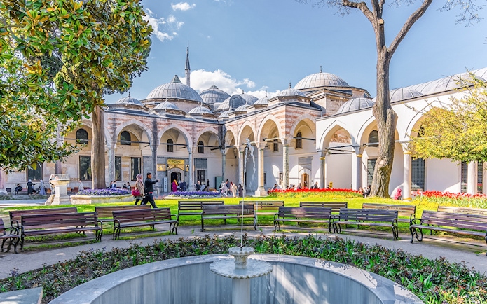 Topkapi Palace Courtyard with benches, fountain, and arched colonnade in Istanbul.