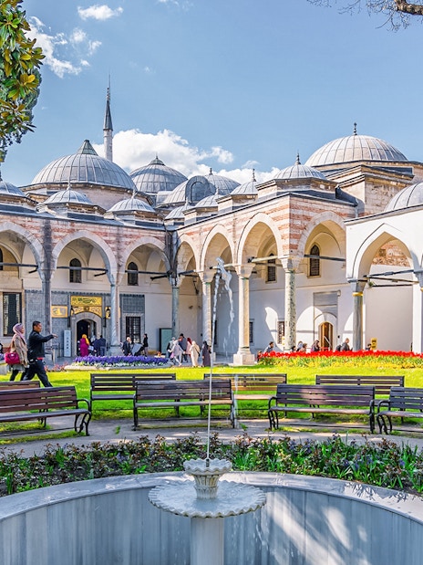 Topkapi Palace Courtyard with benches, fountain, and arched colonnade in Istanbul.