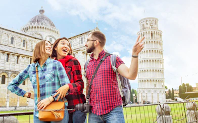 Tourists enjoying a guided tour at the Baptistery and Cathedral with the Leaning Tower of Pisa in the background.
