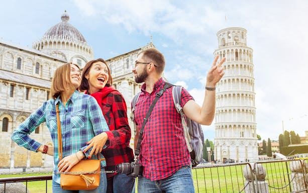 Tourists enjoying a guided tour at the Baptistery and Cathedral with the Leaning Tower of Pisa in the background.