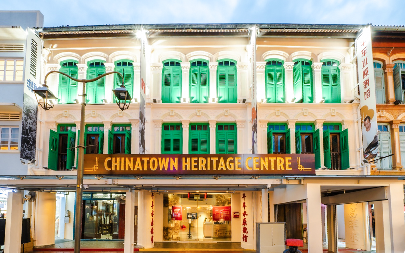 Chinatown Heritage Centre exterior with green shutters and illuminated facade in Singapore.