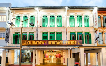 Chinatown Heritage Centre exterior with green shutters and illuminated facade in Singapore.