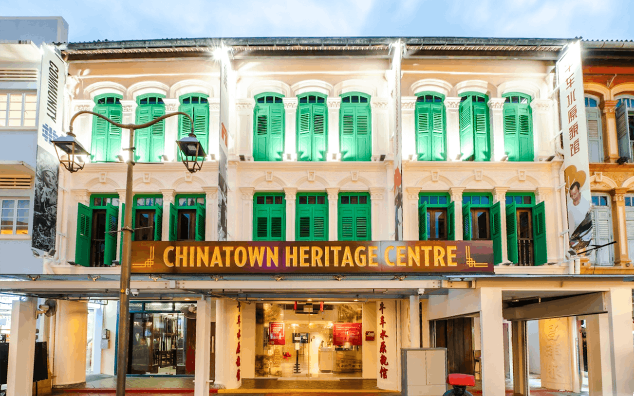 Chinatown Heritage Centre exterior with green shutters and illuminated facade in Singapore.