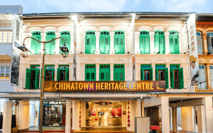 Chinatown Heritage Centre exterior with green shutters and illuminated facade in Singapore.